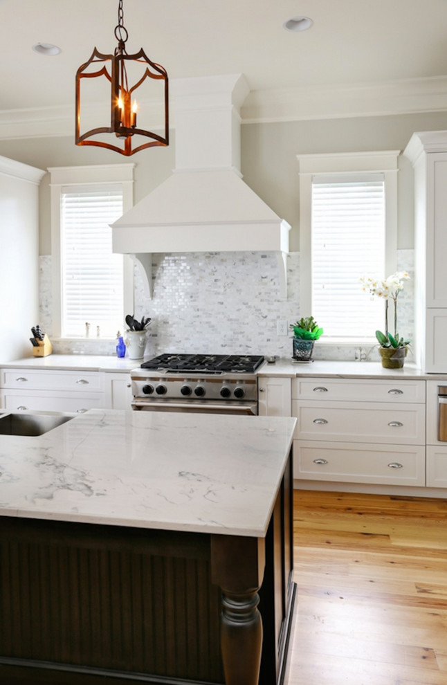 Modern inredning av ett avskilt, mellanstort grå grått kök, med en rustik diskho, skåp i shakerstil, vita skåp, bänkskiva i kvartsit, grått stänkskydd, stänkskydd i stickkakel, rostfria vitvaror, ljust trägolv, en köksö och beiget golv