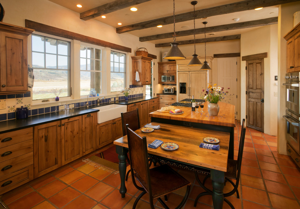 Inspiration for a mid-sized rustic u-shaped terra-cotta tile eat-in kitchen remodel in Denver with a farmhouse sink, shaker cabinets, wood countertops, multicolored backsplash, ceramic backsplash, stainless steel appliances, an island and medium tone wood cabinets