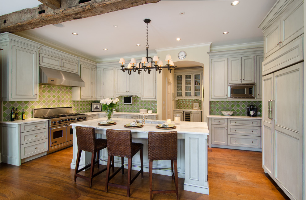 Cette image montre une cuisine américaine en U avec un placard à porte plane, des portes de placard blanches et une crédence verte.