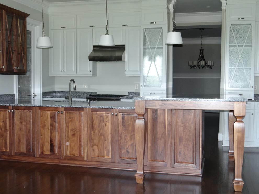 Inspiration for a transitional dark wood floor kitchen remodel in Charlotte with an undermount sink, raised-panel cabinets, medium tone wood cabinets, granite countertops, stainless steel appliances and a peninsula