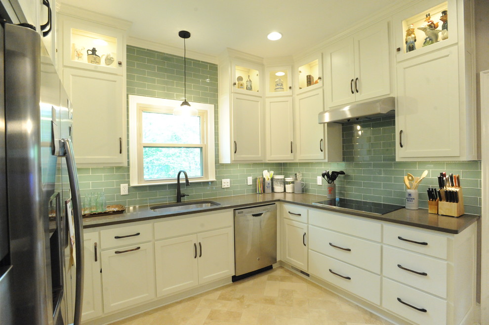Inredning av ett klassiskt u-kök, med en enkel diskho, luckor med infälld panel, vita skåp, bänkskiva i kvarts, grönt stänkskydd, stänkskydd i glaskakel, rostfria vitvaror, travertin golv och en köksö