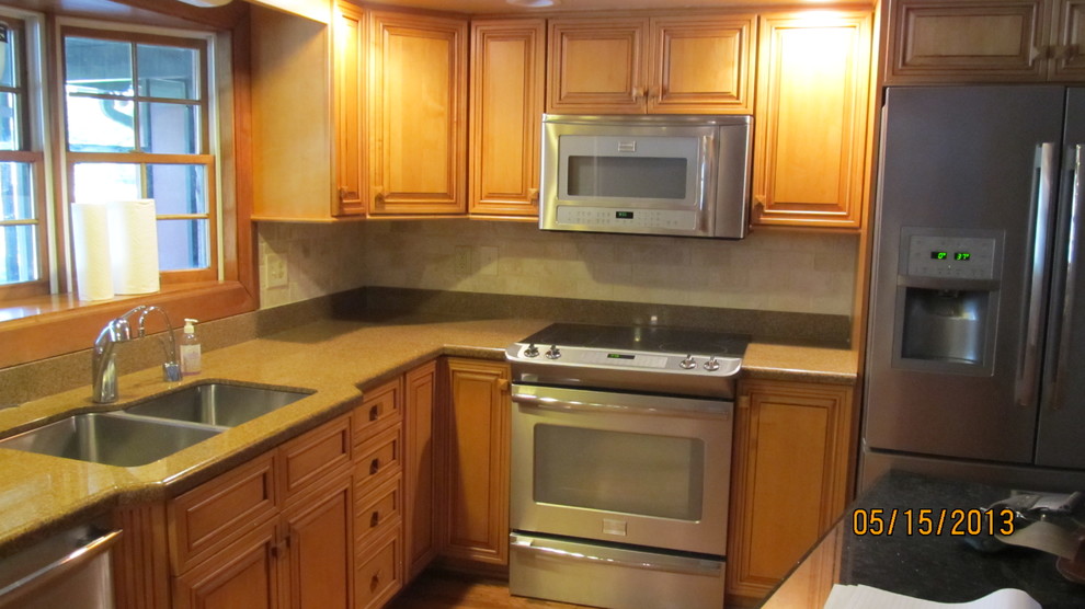 Diseño de cocina contemporánea, grande, con fregadero de doble seno, armarios con paneles con relieve, puertas de armario de madera clara, encimera de laminado, salpicadero beige, salpicadero de azulejos de porcelana, electrodomésticos de acero inoxidable y una isla