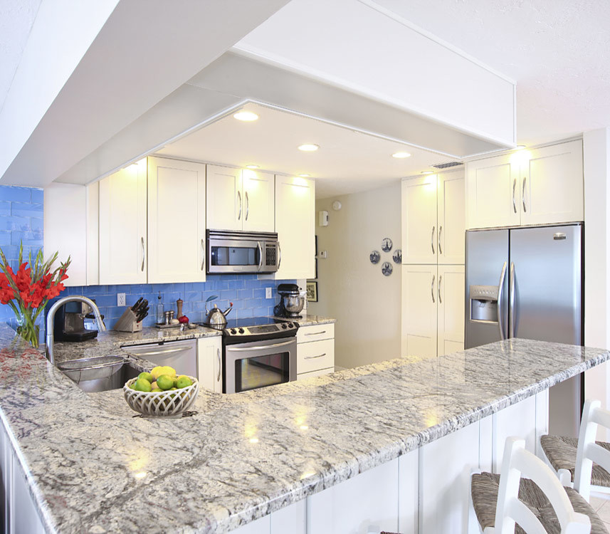 Mid-sized trendy l-shaped limestone floor eat-in kitchen photo in Tampa with a single-bowl sink, recessed-panel cabinets, white cabinets, granite countertops, blue backsplash, ceramic backsplash and stainless steel appliances