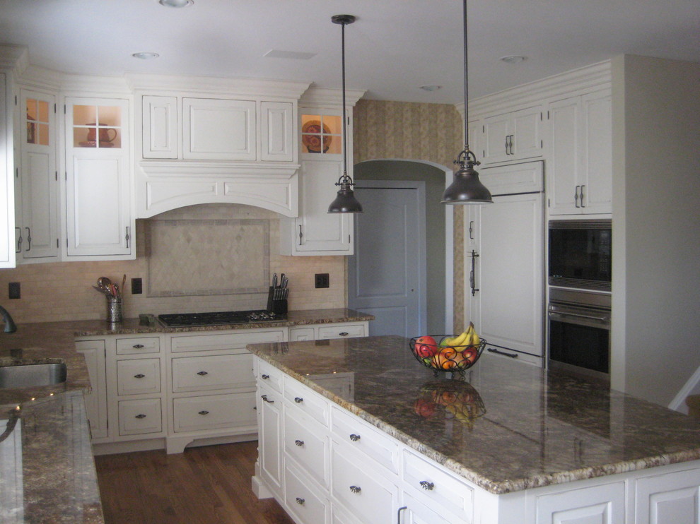 Foto på ett mellanstort vintage kök, med en undermonterad diskho, luckor med upphöjd panel, vita skåp, granitbänkskiva, beige stänkskydd, stänkskydd i stenkakel, vita vitvaror, mellanmörkt trägolv, en köksö och brunt golv