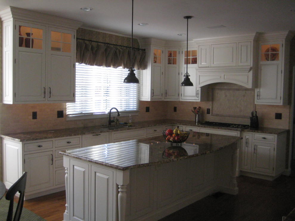 Inredning av ett klassiskt mellanstort kök, med en undermonterad diskho, luckor med upphöjd panel, vita skåp, granitbänkskiva, beige stänkskydd, stänkskydd i stenkakel, vita vitvaror, mellanmörkt trägolv, en köksö och brunt golv