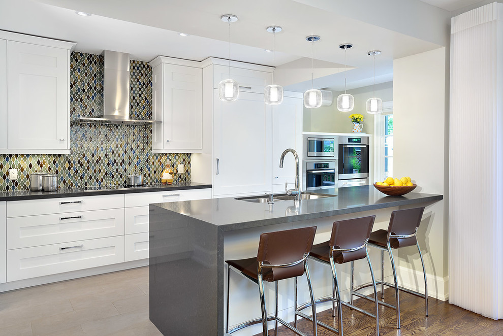 Photo of a contemporary kitchen in Toronto with a double-bowl sink, white cabinets, multi-coloured splashback, stainless steel appliances and recessed-panel cabinets.