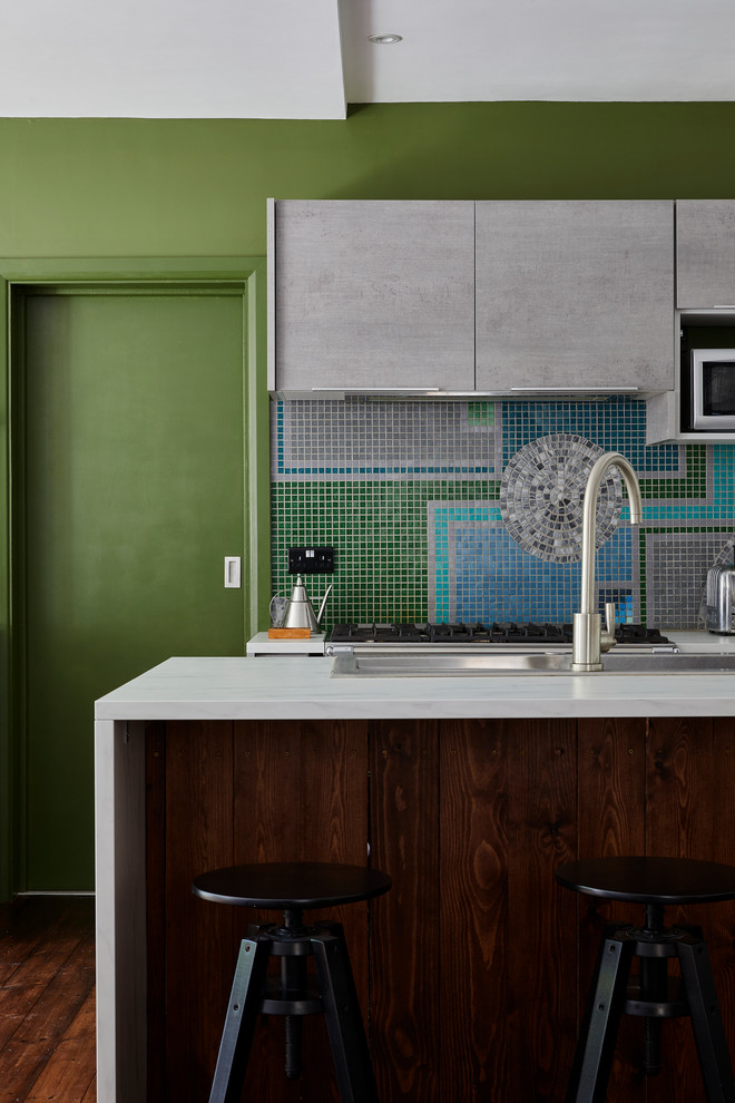 Design ideas for a contemporary kitchen in London with a built-in sink, flat-panel cabinets, grey cabinets, multi-coloured splashback, mosaic tiled splashback, dark hardwood flooring, an island, brown floors and white worktops.