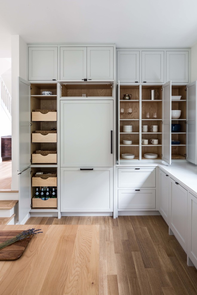 Ejemplo de cocinas en L marinera con armarios estilo shaker, puertas de armario grises, suelo de madera clara, encimeras blancas, electrodomésticos con paneles y suelo beige