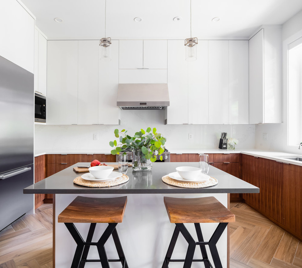 Kitchen - contemporary u-shaped brown floor kitchen idea in Vancouver with an undermount sink, flat-panel cabinets, white cabinets, white backsplash, stainless steel appliances, an island and white countertops