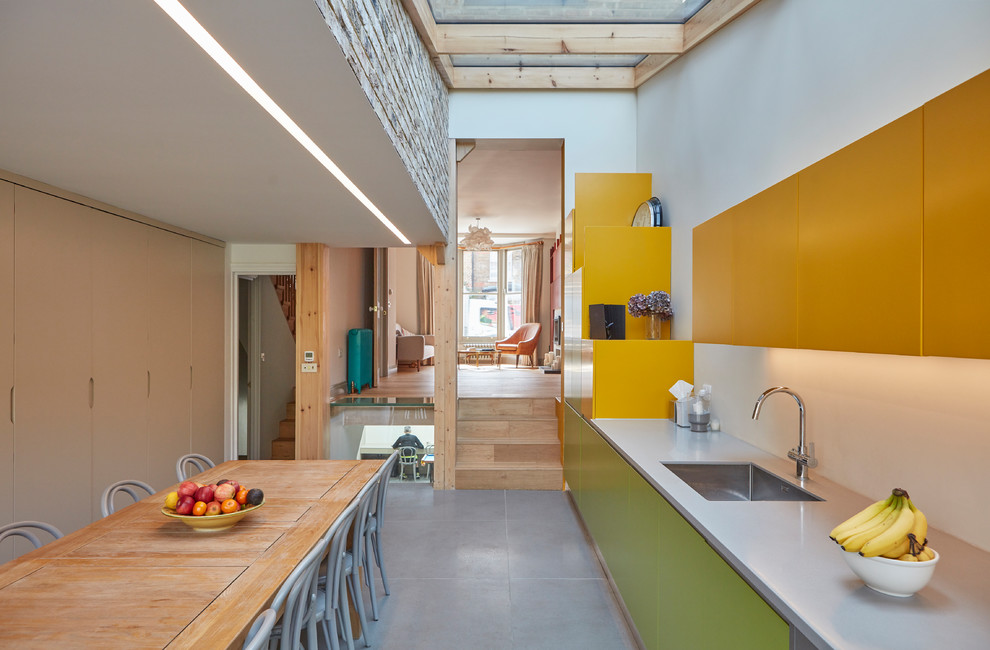 Источник вдохновения для домашнего уюта: прямая кухня среднего размера в современном стиле с обеденным столом, врезной мойкой, плоскими фасадами, серым полом и желтыми фасадами без острова