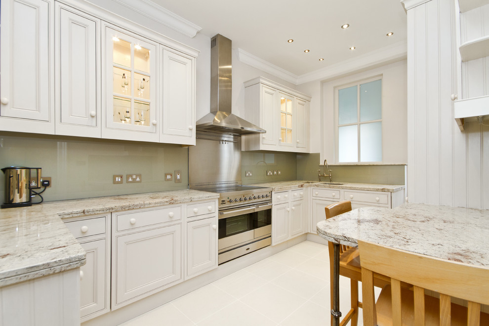 ロンドンにあるトランジショナルスタイルのおしゃれなキッチン (インセット扉のキャビネット、シルバーの調理設備、白いキャビネット、緑のキッチンパネル、ガラス板のキッチンパネル、ステンレスのキッチンパネル) の写真