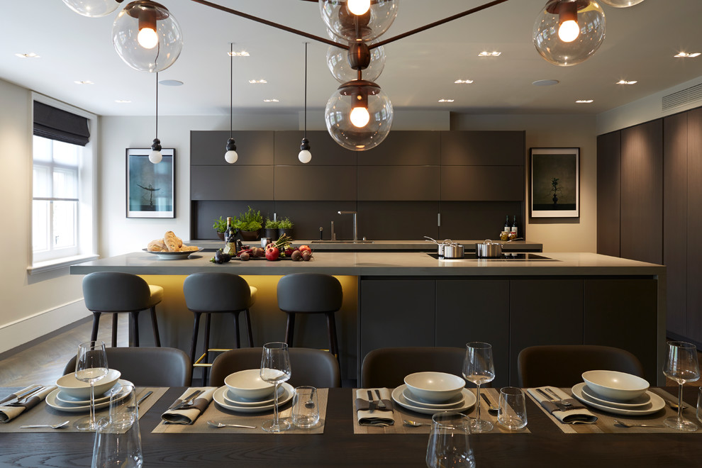 Moderne Wohnküche mit flächenbündigen Schrankfronten, schwarzen Schränken, dunklem Holzboden und Kücheninsel in London