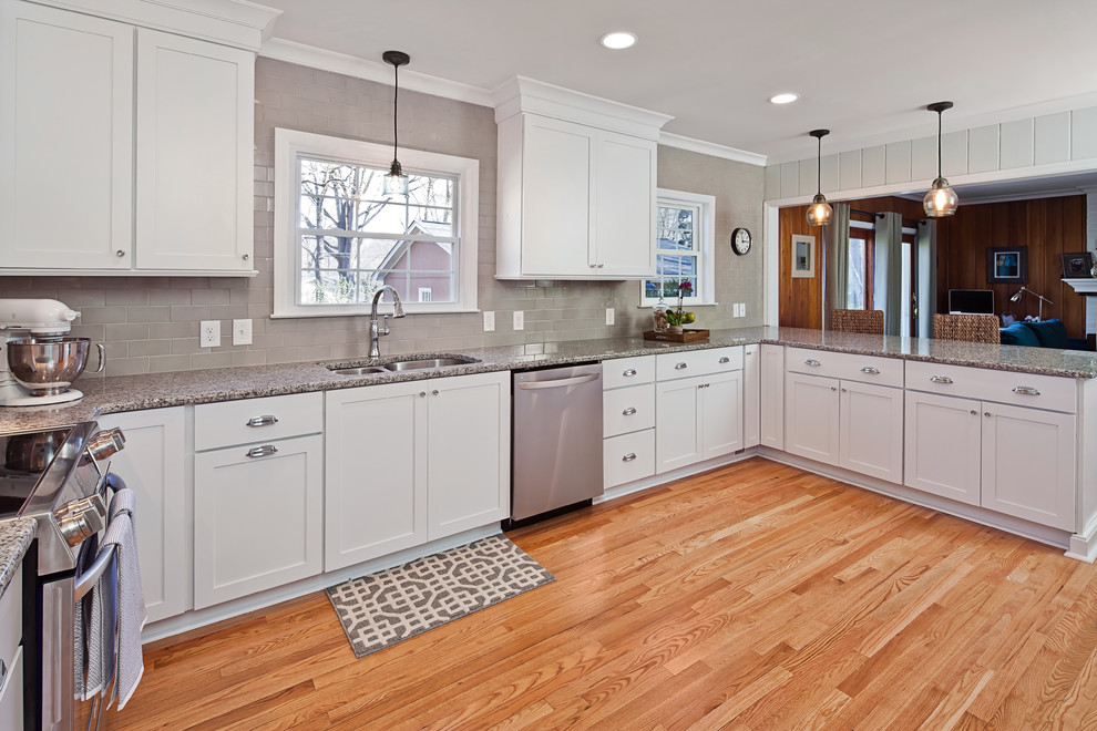 Mid-sized transitional u-shaped light wood floor eat-in kitchen photo in Charlotte with an undermount sink, shaker cabinets, white cabinets, granite countertops, gray backsplash, ceramic backsplash, stainless steel appliances and a peninsula