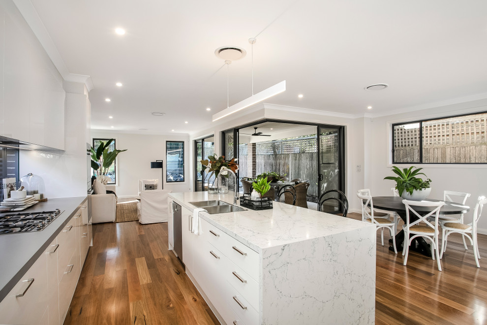 シドニーにある広いコンテンポラリースタイルのおしゃれなキッチン (アンダーカウンターシンク、フラットパネル扉のキャビネット、白いキャビネット、無垢フローリング、茶色い床、白いキッチンカウンター) の写真