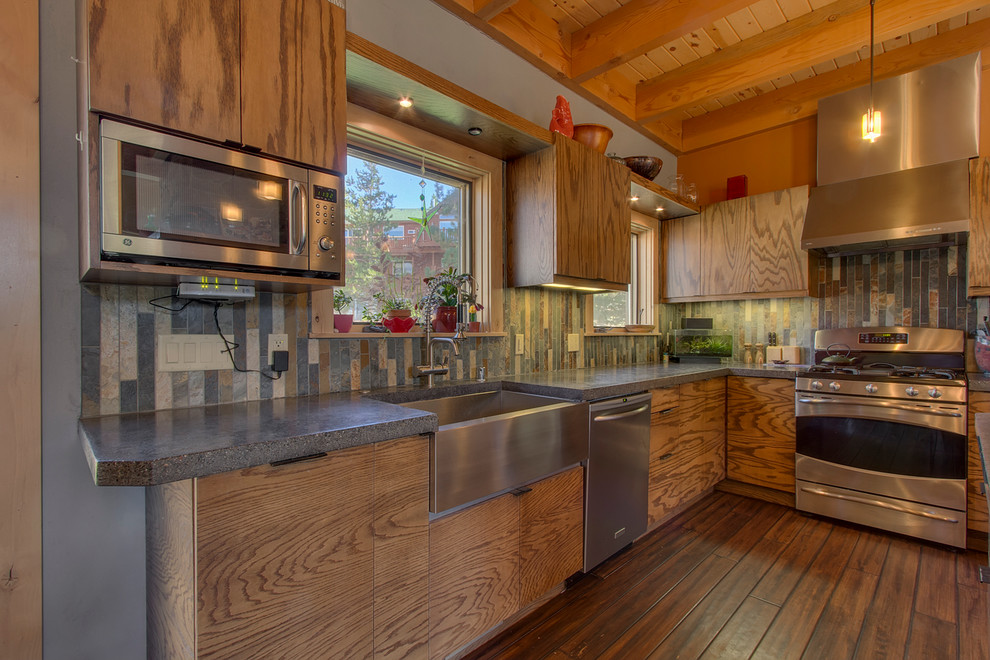 Foto på ett stort rustikt kök, med en rustik diskho, släta luckor, skåp i mellenmörkt trä, bänkskiva i betong, flerfärgad stänkskydd, stänkskydd i skiffer, rostfria vitvaror, mörkt trägolv, en halv köksö och brunt golv