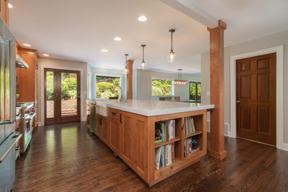 Inspiration for a large timeless single-wall dark wood floor and brown floor eat-in kitchen remodel in Seattle with a farmhouse sink, shaker cabinets, medium tone wood cabinets, quartz countertops, white backsplash, subway tile backsplash, stainless steel appliances, an island and white countertops