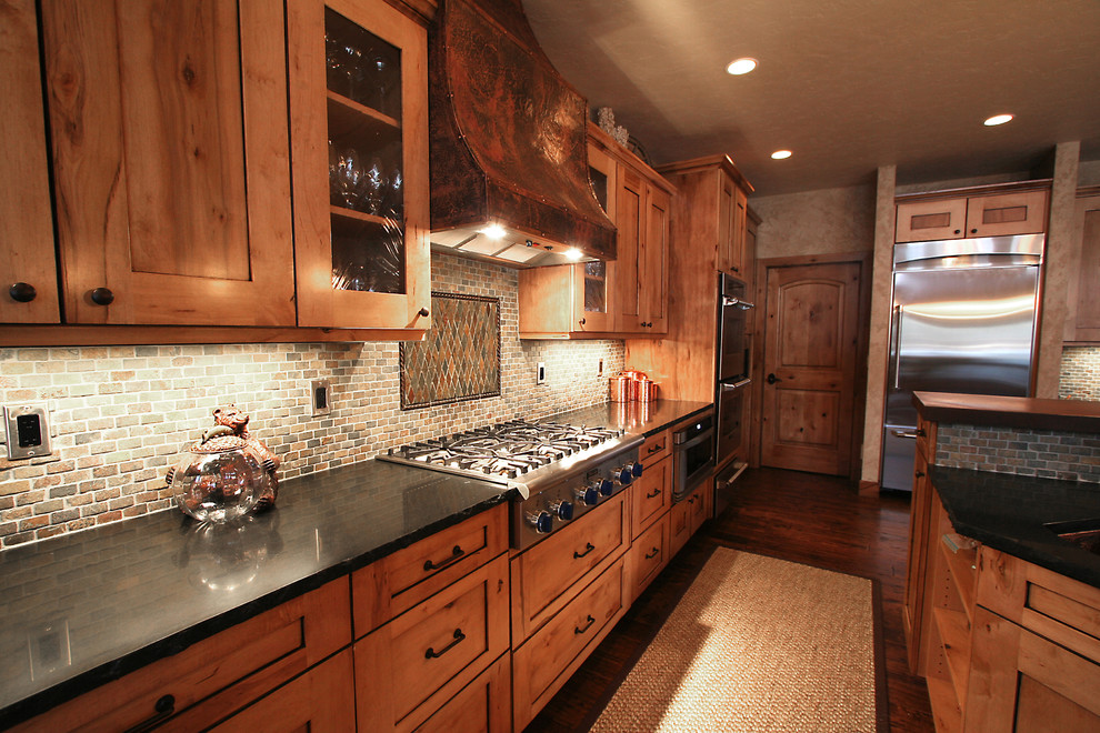 Inspiration for a large rustic u-shaped medium tone wood floor eat-in kitchen remodel in Seattle with an undermount sink, shaker cabinets, medium tone wood cabinets, solid surface countertops, multicolored backsplash, mosaic tile backsplash, stainless steel appliances and two islands