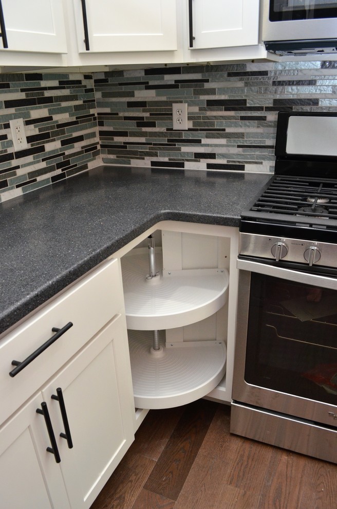 Example of a mid-sized transitional l-shaped brown floor eat-in kitchen design in Other with an undermount sink, shaker cabinets, white cabinets, solid surface countertops, multicolored backsplash, matchstick tile backsplash, stainless steel appliances, an island and blue countertops