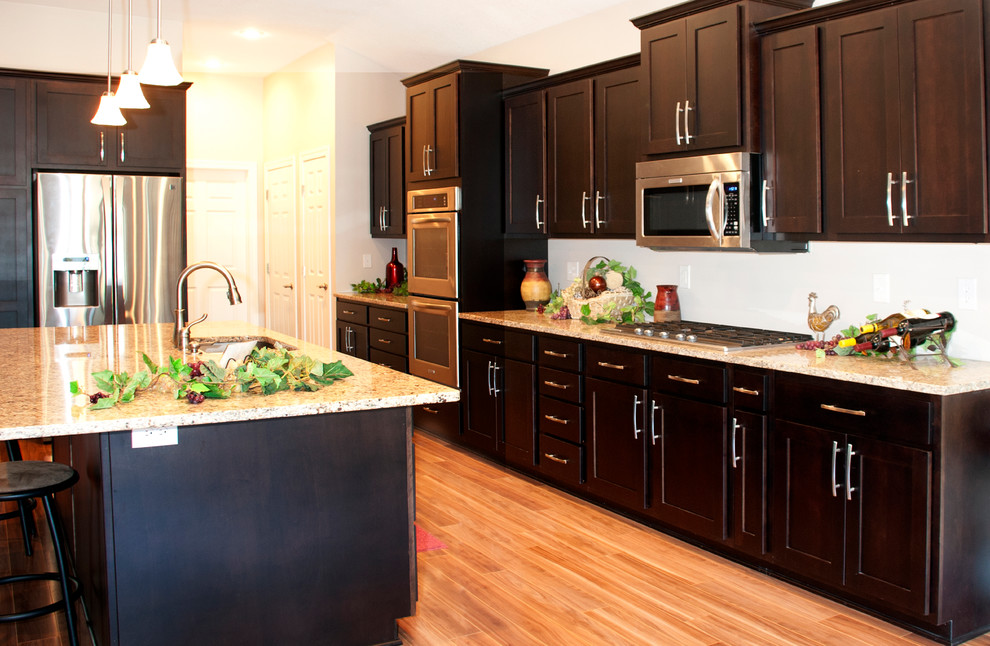 Exempel på ett klassiskt kök, med luckor med upphöjd panel, skåp i mellenmörkt trä, granitbänkskiva, vitt stänkskydd, stänkskydd i keramik och rostfria vitvaror