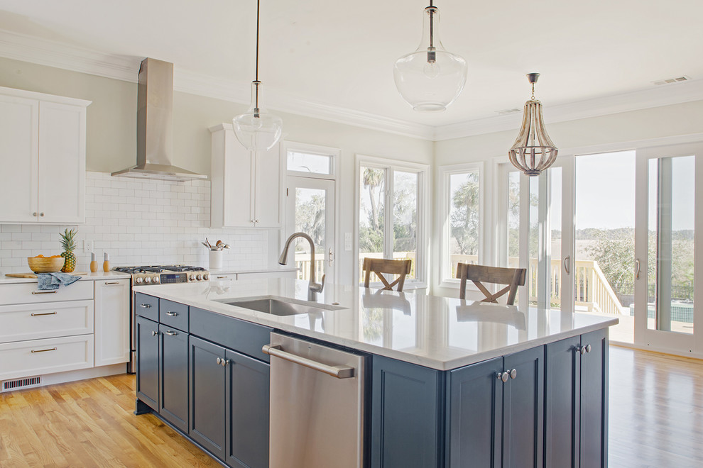 Inspiration for a large transitional l-shaped medium tone wood floor and brown floor open concept kitchen remodel in Other with an undermount sink, shaker cabinets, blue cabinets, quartz countertops, white backsplash, subway tile backsplash, stainless steel appliances, an island and white countertops