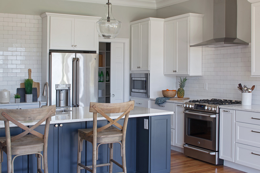 Exempel på ett stort klassiskt vit vitt kök, med en undermonterad diskho, skåp i shakerstil, blå skåp, bänkskiva i kvarts, vitt stänkskydd, stänkskydd i tunnelbanekakel, rostfria vitvaror, mellanmörkt trägolv, en köksö och brunt golv