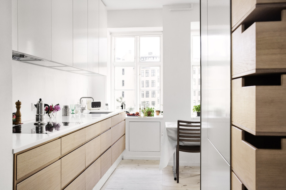 This is an example of a small modern single-wall kitchen/diner in Other with flat-panel cabinets, light wood cabinets, a single-bowl sink, recycled glass countertops, white splashback, glass sheet splashback, white appliances, painted wood flooring and an island.