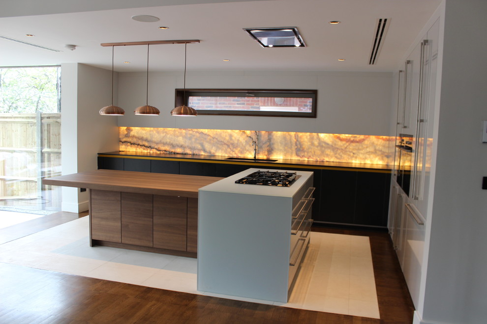 Eat-in kitchen - mid-sized contemporary l-shaped eat-in kitchen idea in London with an integrated sink, flat-panel cabinets, orange backsplash, glass sheet backsplash, black appliances and an island