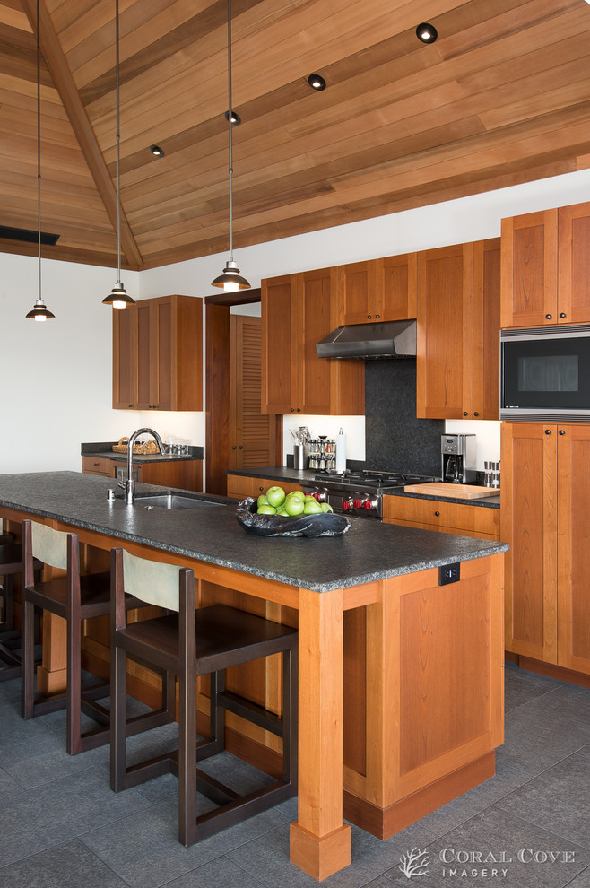 Küche mit hellbraunen Holzschränken, Granit-Arbeitsplatte, Küchengeräten aus Edelstahl und Kücheninsel in Hawaii