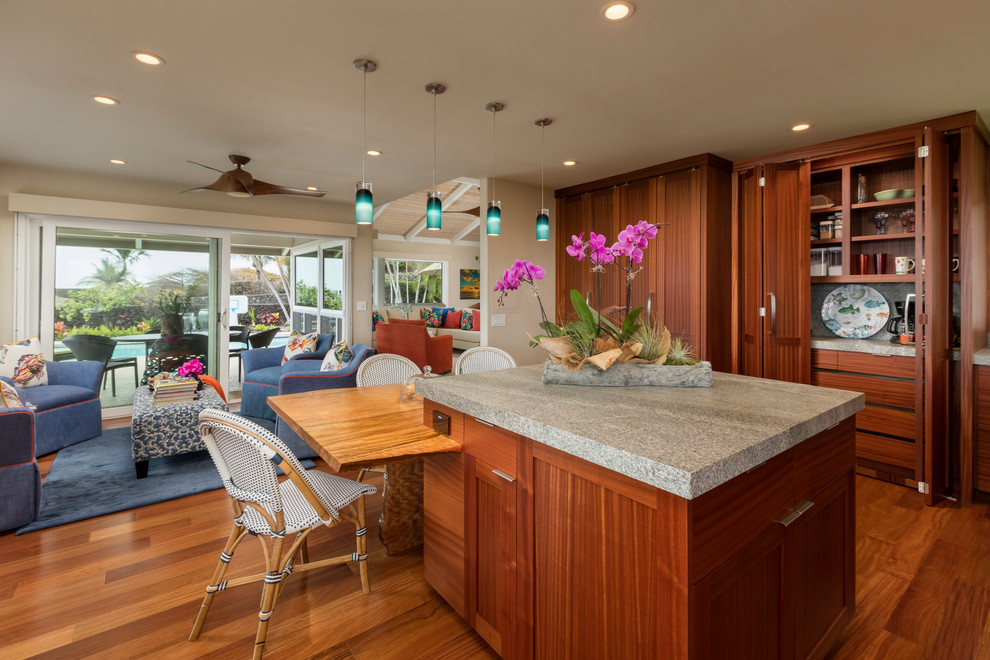 Photo of a large world-inspired u-shaped kitchen/diner in Hawaii with a built-in sink, flat-panel cabinets, dark wood cabinets, granite worktops, white splashback, glass tiled splashback, stainless steel appliances, dark hardwood flooring, an island and brown floors.