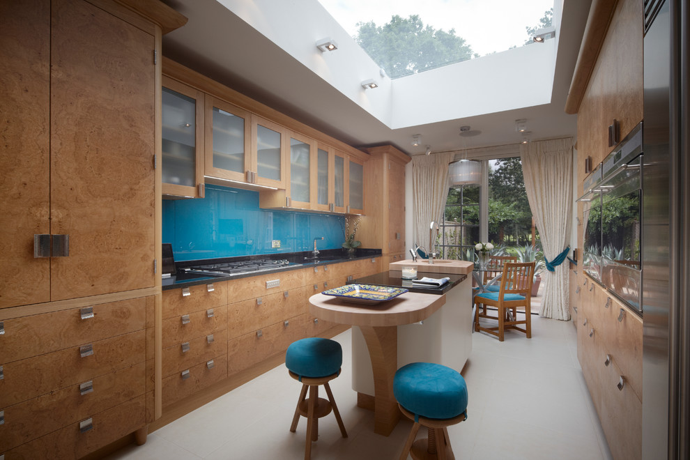 Large contemporary galley kitchen/diner in Other with a double-bowl sink, flat-panel cabinets, medium wood cabinets, granite worktops, blue splashback, glass sheet splashback, integrated appliances, ceramic flooring and an island.