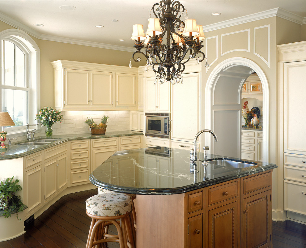 Large french country u-shaped dark wood floor enclosed kitchen photo in San Diego with a double-bowl sink, recessed-panel cabinets, beige cabinets, white backsplash, subway tile backsplash, paneled appliances, marble countertops and an island