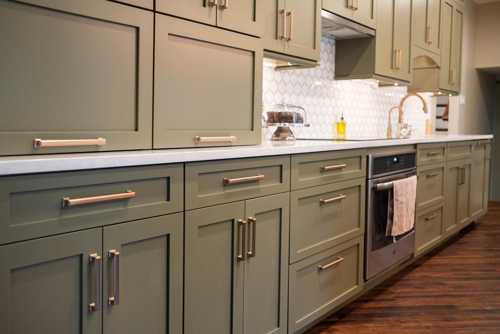 フィラデルフィアにある高級な広いトランジショナルスタイルのおしゃれなキッチン (アンダーカウンターシンク、フラットパネル扉のキャビネット、緑のキャビネット、珪岩カウンター、白いキッチンパネル、セラミックタイルのキッチンパネル、シルバーの調理設備、無垢フローリング、茶色い床、白いキッチンカウンター) の写真