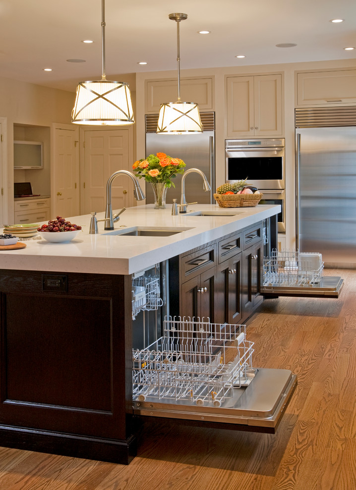 Example of a large classic u-shaped medium tone wood floor kitchen design in Philadelphia with an undermount sink, recessed-panel cabinets, dark wood cabinets, stainless steel appliances, solid surface countertops and an island