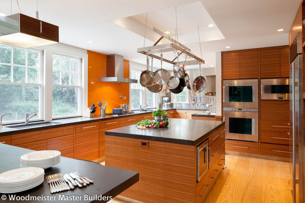 Zweizeilige, Mittelgroße Moderne Küche mit flächenbündigen Schrankfronten, hellbraunen Holzschränken, Granit-Arbeitsplatte, Küchengeräten aus Edelstahl, hellem Holzboden und Kücheninsel in Boston