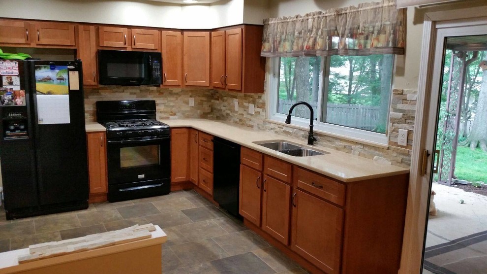 Example of a mid-sized trendy l-shaped enclosed kitchen design in St Louis with an undermount sink, shaker cabinets, medium tone wood cabinets, black appliances and no island
