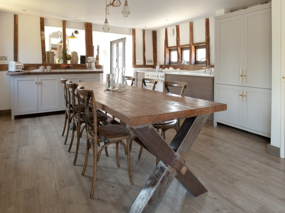 Inredning av ett rustikt mellanstort kök, med luckor med infälld panel, vita skåp, träbänkskiva, vita vitvaror, laminatgolv och grått golv