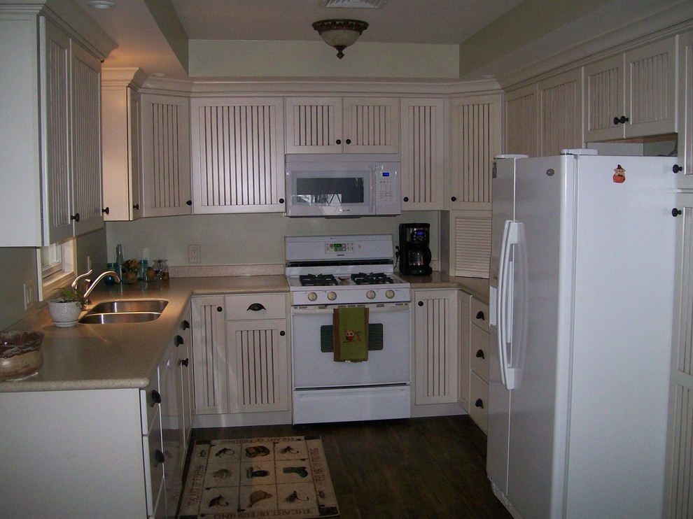 Foto på ett vintage kök, med en undermonterad diskho, luckor med profilerade fronter, beige skåp och vita vitvaror