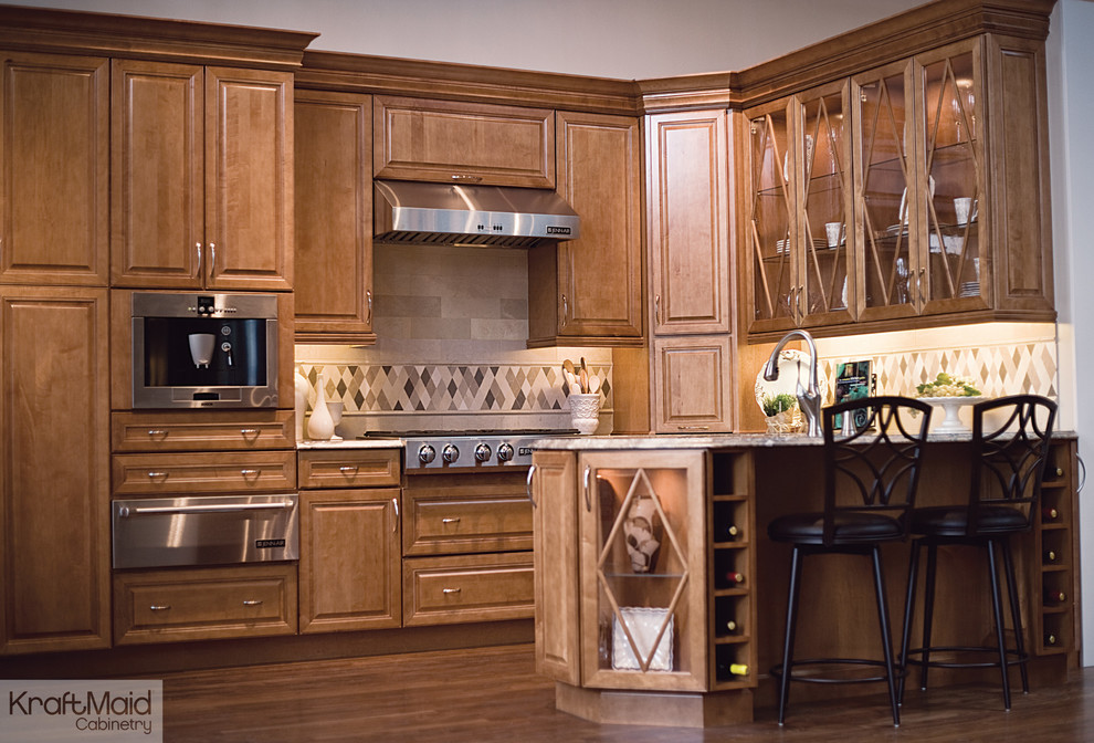 Klassisk inredning av ett litet kök, med luckor med upphöjd panel, skåp i ljust trä, rostfria vitvaror och en halv köksö