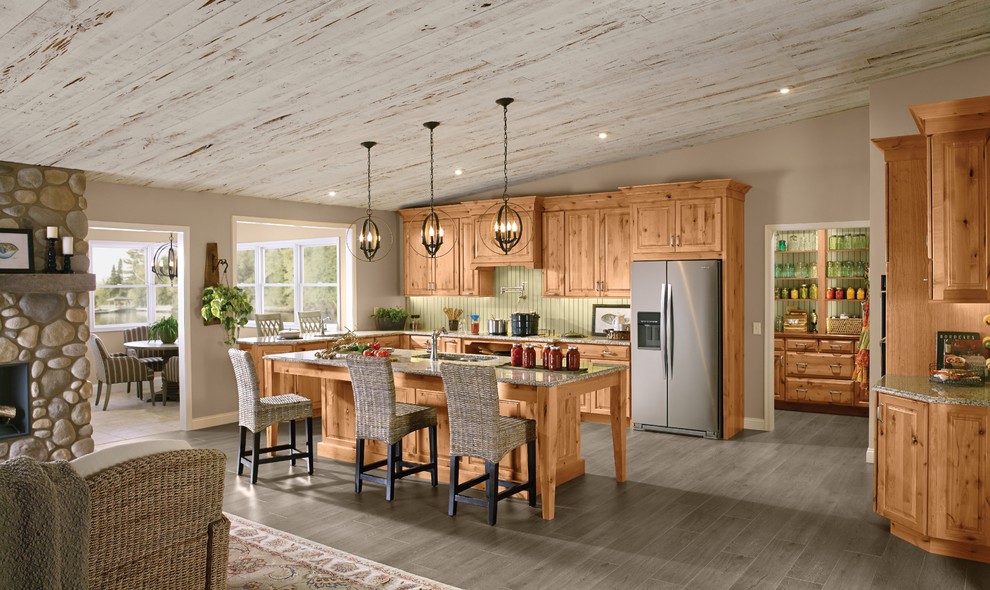 Exempel på ett stort rustikt brun brunt kök, med en dubbel diskho, luckor med upphöjd panel, skåp i ljust trä, granitbänkskiva, rostfria vitvaror, mellanmörkt trägolv, en köksö och brunt golv
