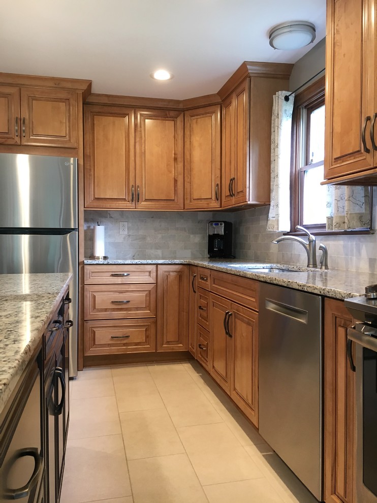 Example of a mid-sized classic l-shaped ceramic tile and beige floor eat-in kitchen design in Other with a double-bowl sink, raised-panel cabinets, medium tone wood cabinets, granite countertops, beige backsplash, marble backsplash, stainless steel appliances, an island and beige countertops