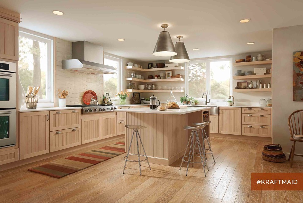 Lantlig inredning av ett mellanstort kök, med en rustik diskho, luckor med infälld panel, skåp i ljust trä, vitt stänkskydd, rostfria vitvaror, ljust trägolv och en köksö