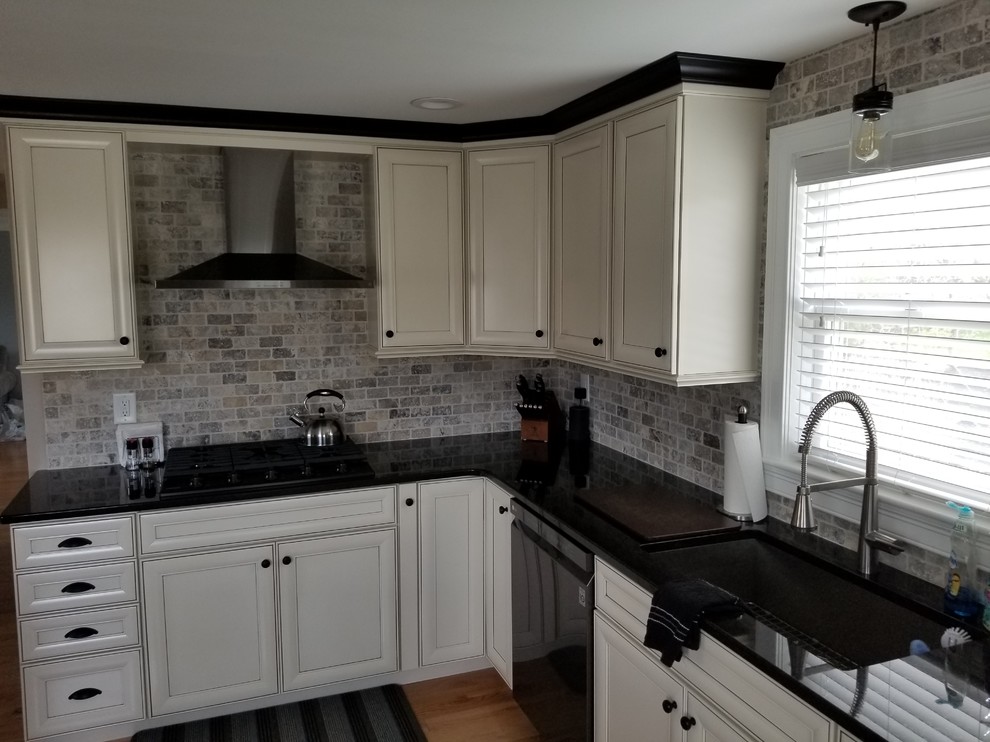 Wohnküche mit profilierten Schrankfronten, weißen Schränken, Granit-Arbeitsplatte, bunter Rückwand, Küchengeräten aus Edelstahl, braunem Holzboden, Kücheninsel und rosa Arbeitsplatte in Boston