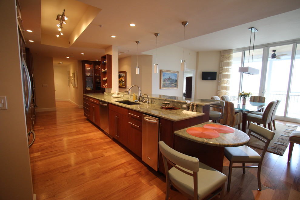 Foto di una grande cucina minimal con lavello sottopiano, ante lisce, ante in legno bruno, top in granito, elettrodomestici in acciaio inossidabile, parquet scuro e pavimento marrone