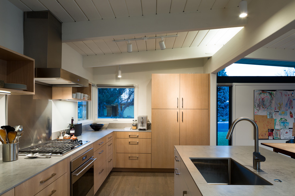 Exemple d'une cuisine américaine rétro en L et bois clair de taille moyenne avec un évier 1 bac, un placard à porte plane, une crédence grise, un sol en bois brun et îlot.