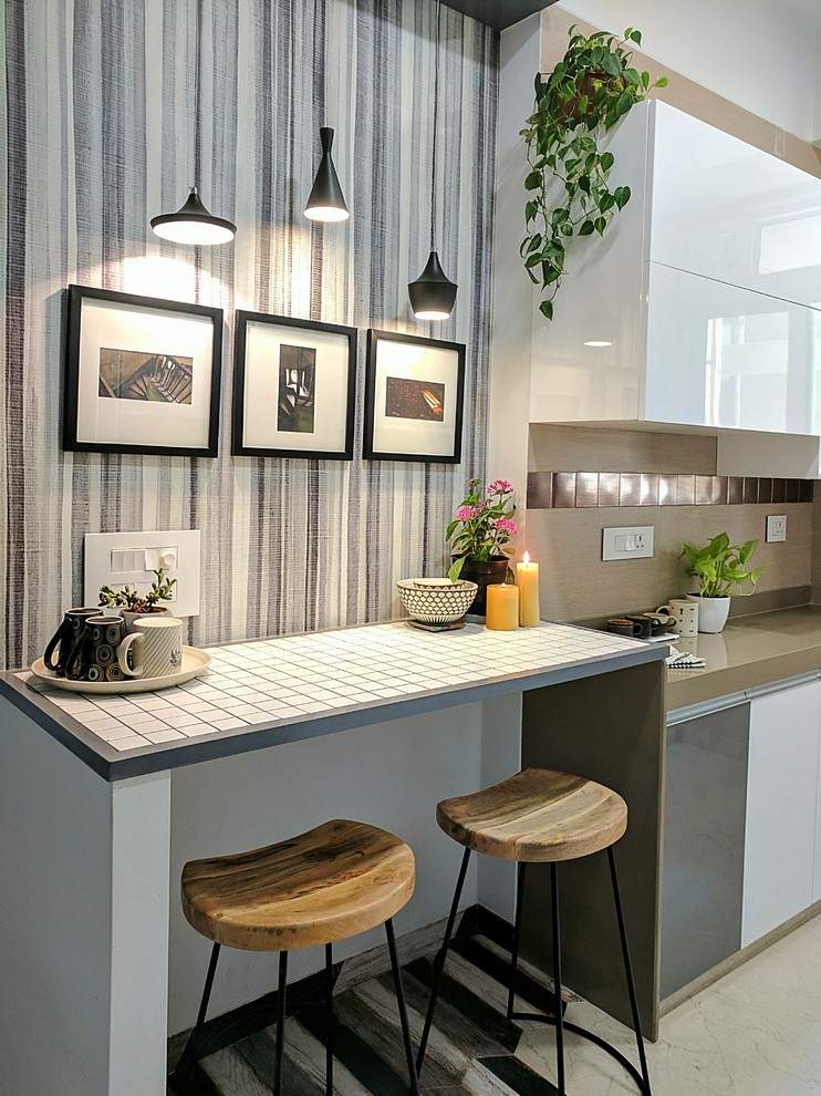На фото: кухня в скандинавском стиле с плоскими фасадами, белыми фасадами, фартуком цвета металлик, фартуком из металлической плитки и бежевой столешницей