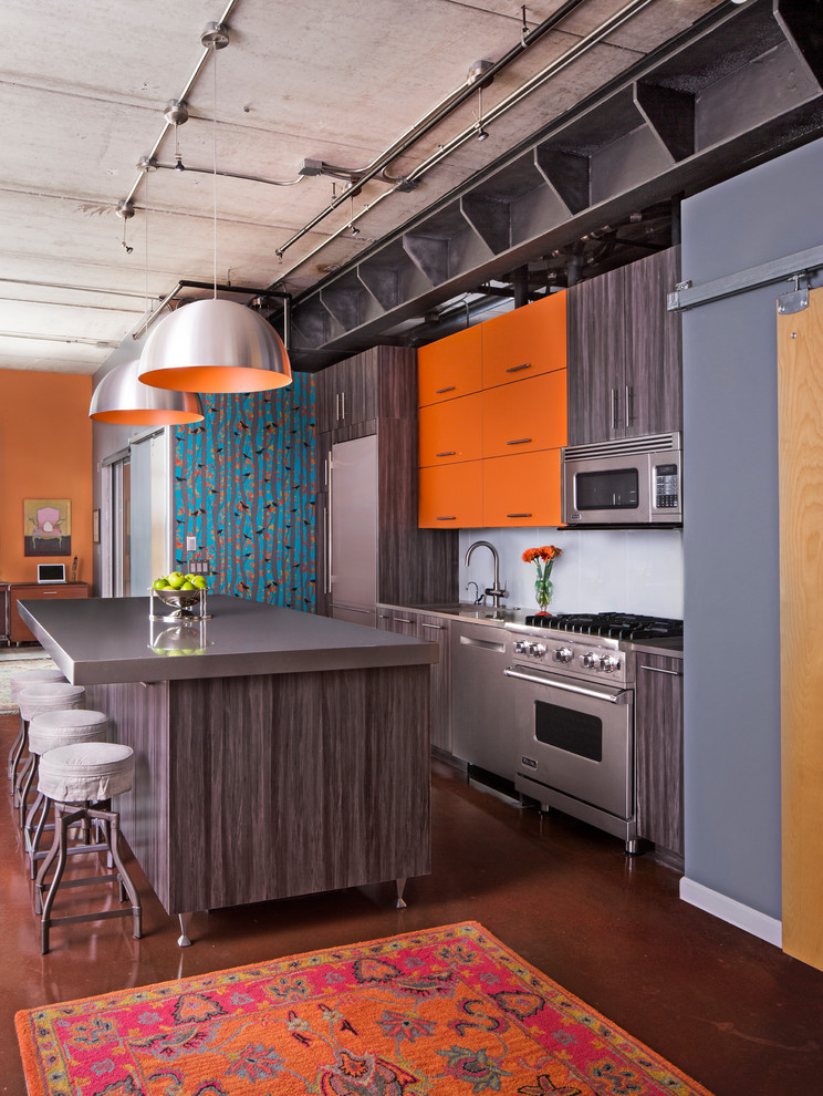 Идея дизайна: прямая кухня-гостиная среднего размера в современном стиле с врезной мойкой, плоскими фасадами, оранжевыми фасадами, гранитной столешницей, синим фартуком, фартуком из стеклянной плитки, техникой из нержавеющей стали, бетонным полом и островом