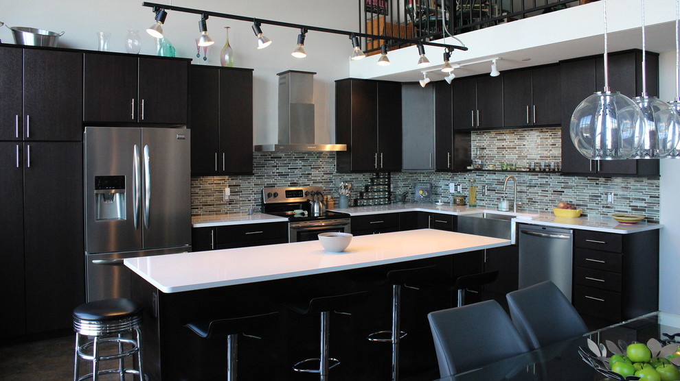 Example of a trendy l-shaped concrete floor open concept kitchen design in Other with a farmhouse sink, flat-panel cabinets, black cabinets, multicolored backsplash, glass tile backsplash, stainless steel appliances and an island