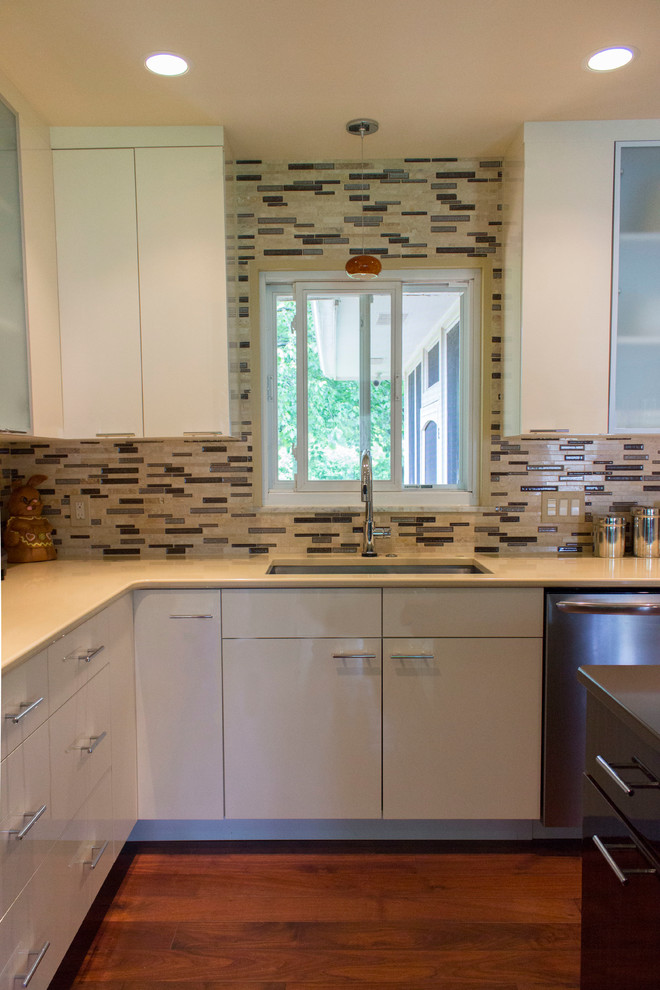 Modern inredning av ett mellanstort kök, med en undermonterad diskho, släta luckor, vita skåp, granitbänkskiva, flerfärgad stänkskydd, stänkskydd i glaskakel, rostfria vitvaror, mellanmörkt trägolv och en köksö
