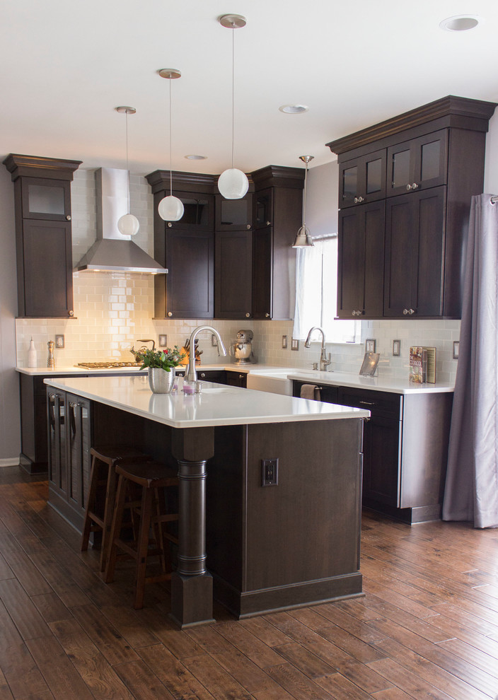 Modern inredning av ett u-kök, med en rustik diskho, luckor med infälld panel, skåp i mörkt trä, vitt stänkskydd, stänkskydd i tunnelbanekakel, rostfria vitvaror, mörkt trägolv och en köksö