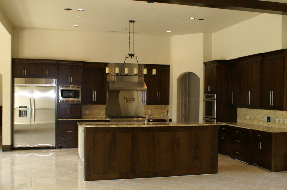 Exempel på ett stort medelhavsstil kök, med skåp i shakerstil, skåp i mörkt trä, granitbänkskiva, beige stänkskydd, stänkskydd i mosaik, rostfria vitvaror, kalkstensgolv och flera köksöar